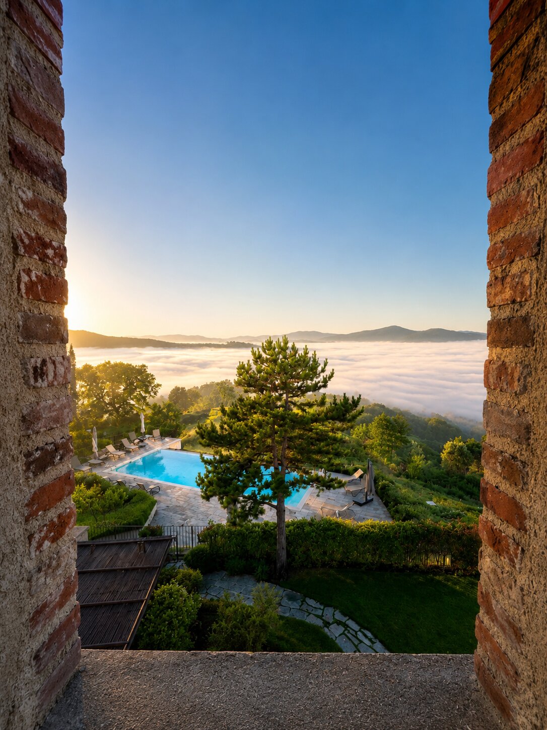 View through a stone archway of the infinity pool above a cloud-filled Niccone Valley at sunrise
