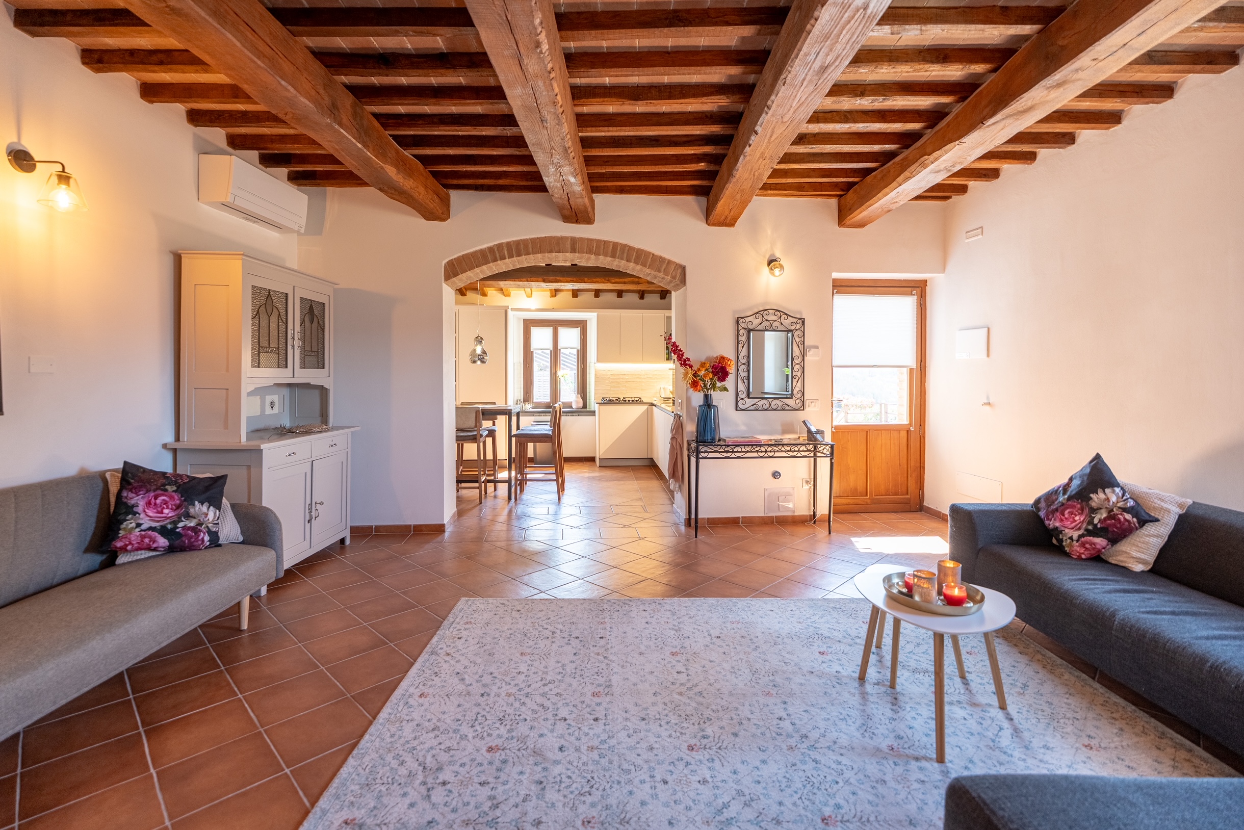 Casa Luna open-plan living room with original timber beams, arched kitchen entrance and terracotta floors