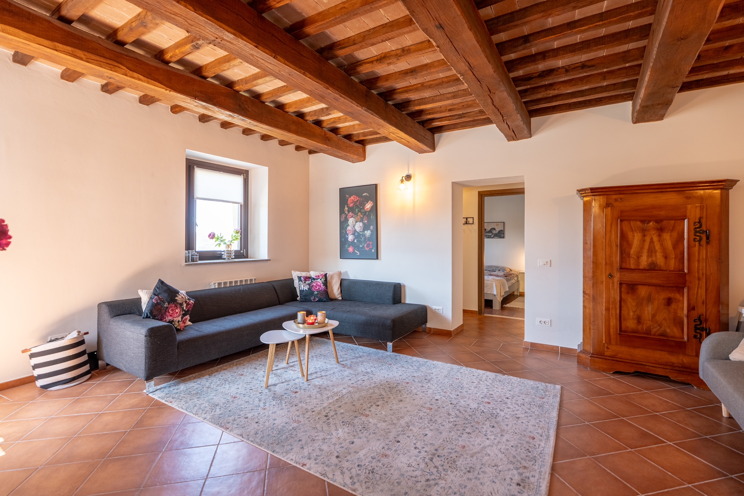 Living room with exposed timber beams, antique armoire and modern sofas