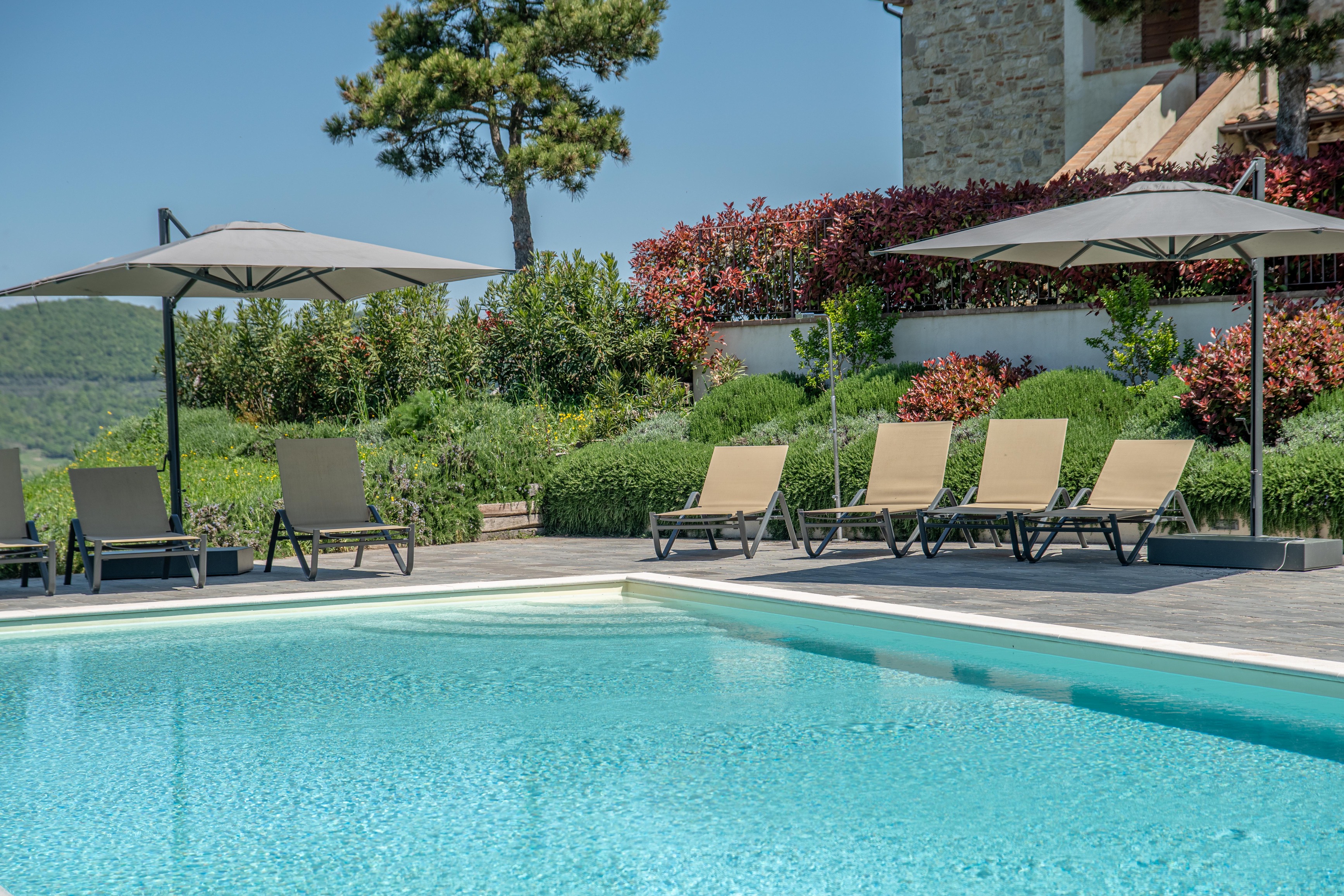 Infinity pool sun terrace with loungers and Umbrian hill views
